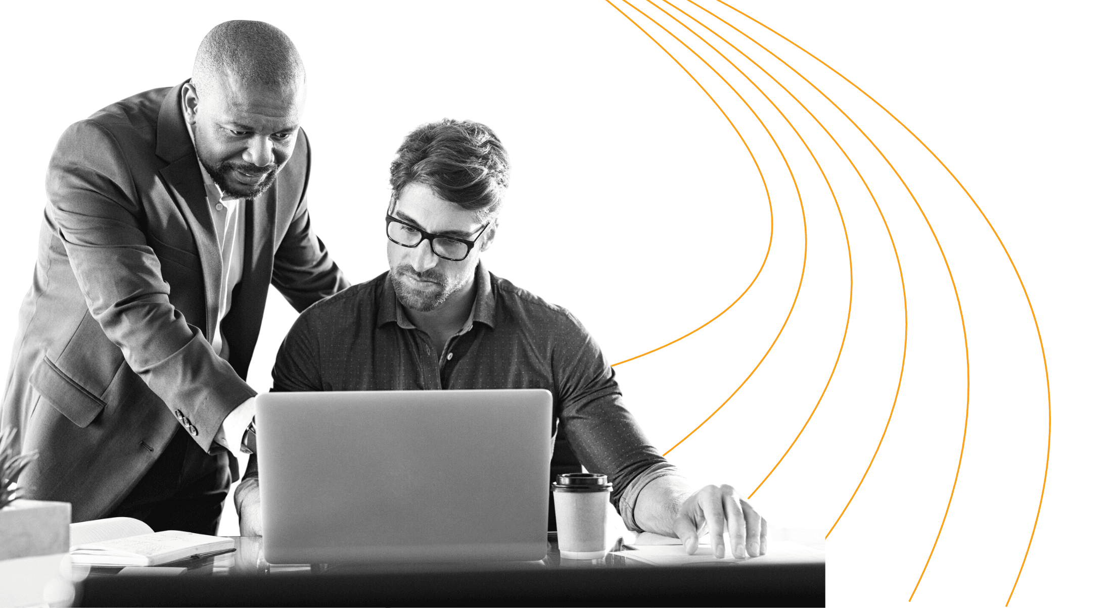 Two men working together at a desk with a laptop.