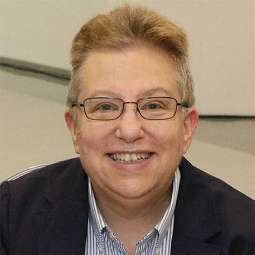 Headshot of Cindy Rizzo, principal, Cindy Rizzo Consulting, wearing glasses, a pinstriped shirt, and dark jacket.