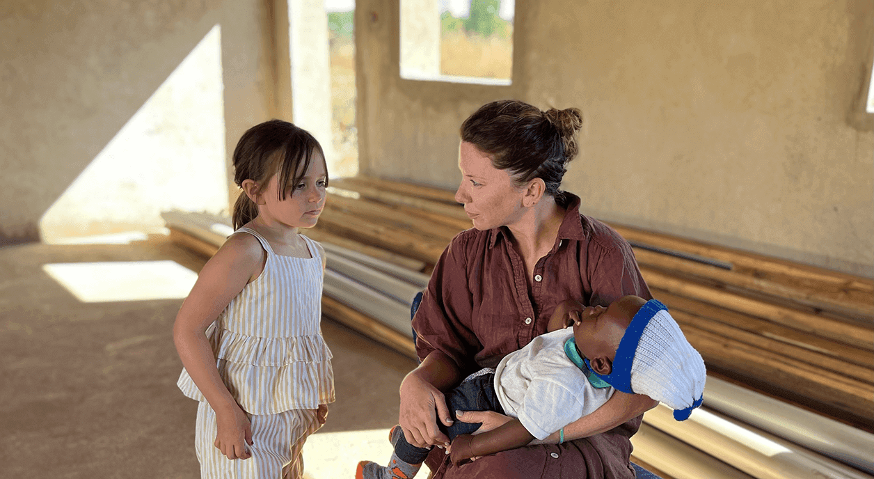 A woman and a young girl taking care of a baby.