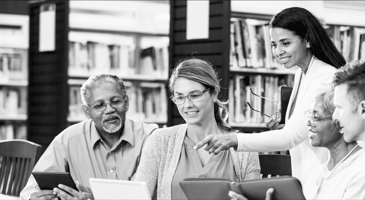 Diverse library patrons at a table looking at tablets. kali9/Getty Images