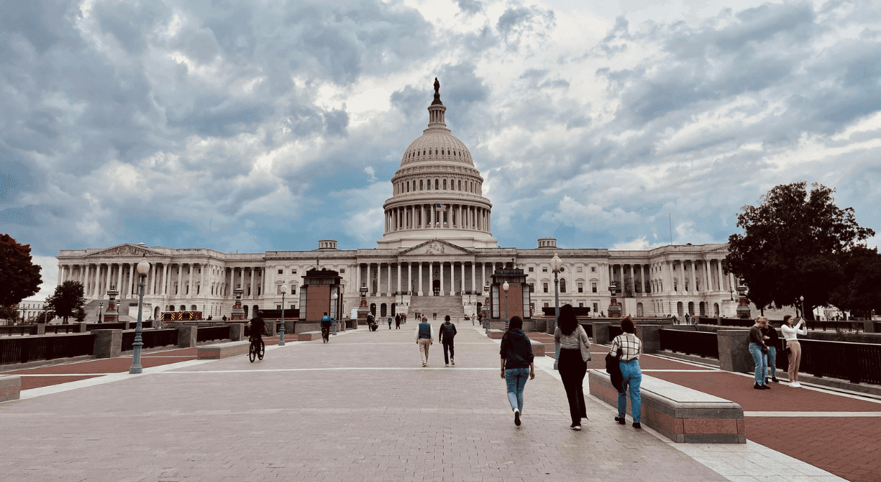 A wide shot of the capital building with people around it.