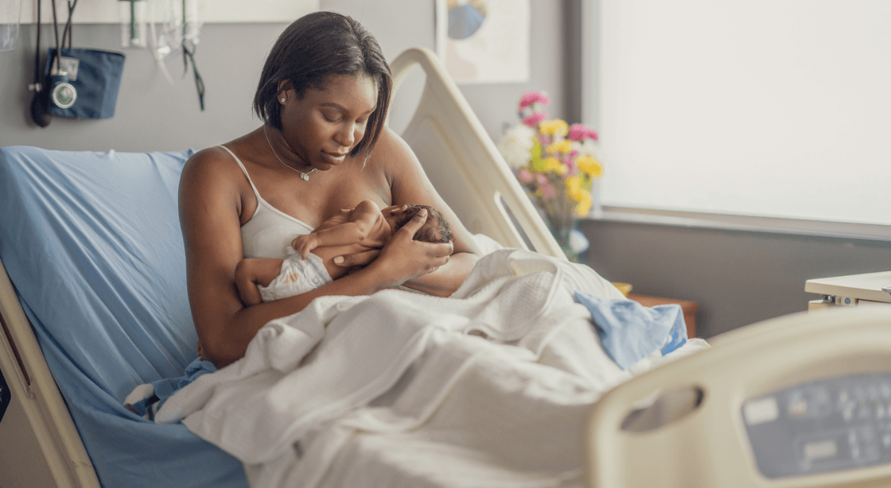 A Black woman nursing her new born baby.