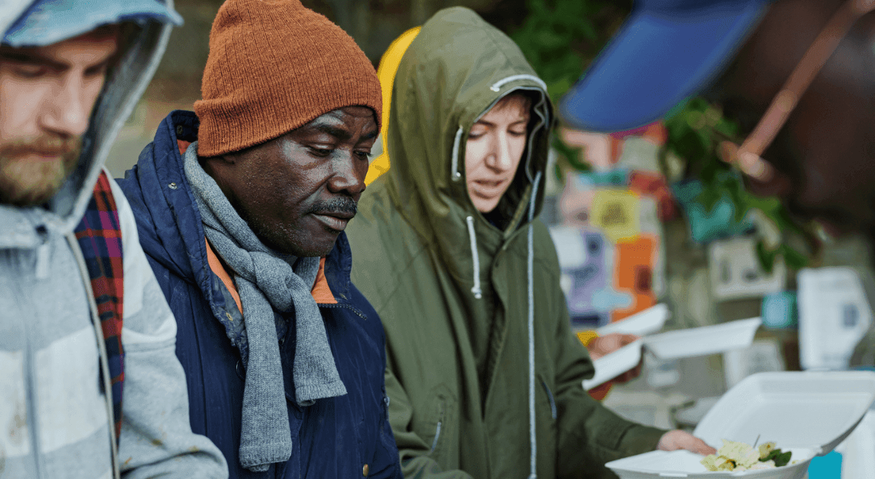Homeless people getting served food at a soup kitchen.